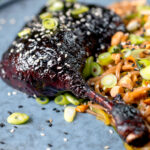 Close-up sticky hoisin baked duck leg with soba noodle salad.