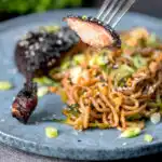 A portion of sticky roast hoisin duck leg on a fork.