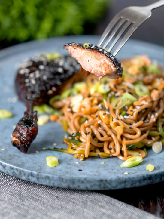 A portion of sticky roast hoisin duck leg on a fork.