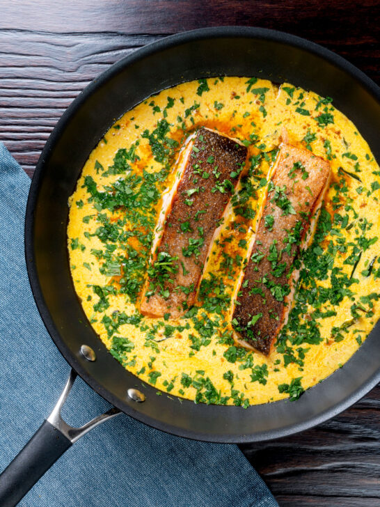 Overhead Indian salmon fillet curry with a yoghurt sauce in the cooking pan.