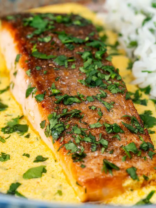 Close-up Indian salmon fillet curry with crispy skin in a yoghurt sauce.