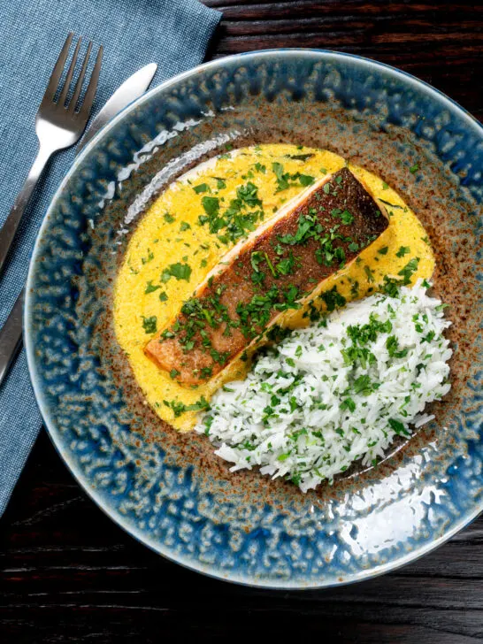 Overhead Indian salmon fillet curry with a yoghurt sauce served with rice.