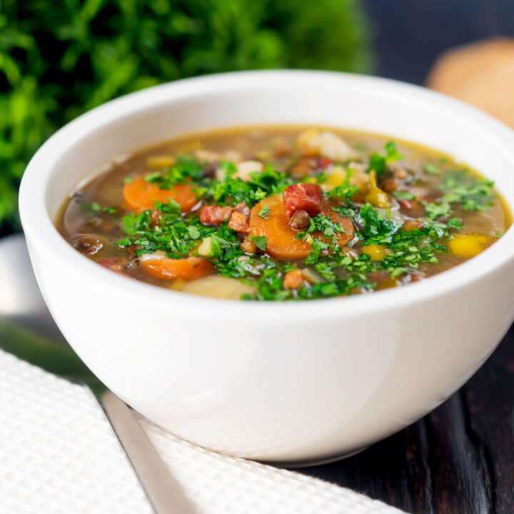 Easy lentil and bacon soup with carrots, potatoes and parsnip in broth.