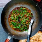 Overhead pork mince curry served in a wok with naan bread.