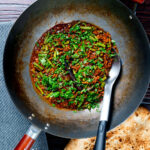 Overhead pork mince curry served in a wok with naan bread featuring a title overlay.