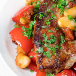 Close-up oven-baked pork loin steaks with chorizo, peppers and beans in a honey glaze.
