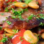 Close-up oven-roasted pork loin steaks with chorizo, peppers and beans in a honey glaze featuring a title overlay.