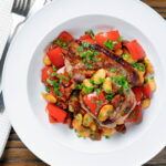 Overhead oven-roasted pork loin steaks with chorizo, peppers and beans in a honey glaze.
