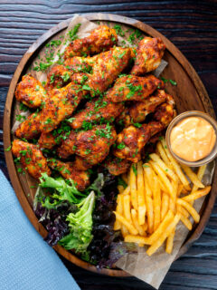 Overhead peri peri chicken wings with fries, spicy mayonnaise and salad.