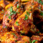 Close-up peri peri chicken wings with fries and spicy mayonnaise.