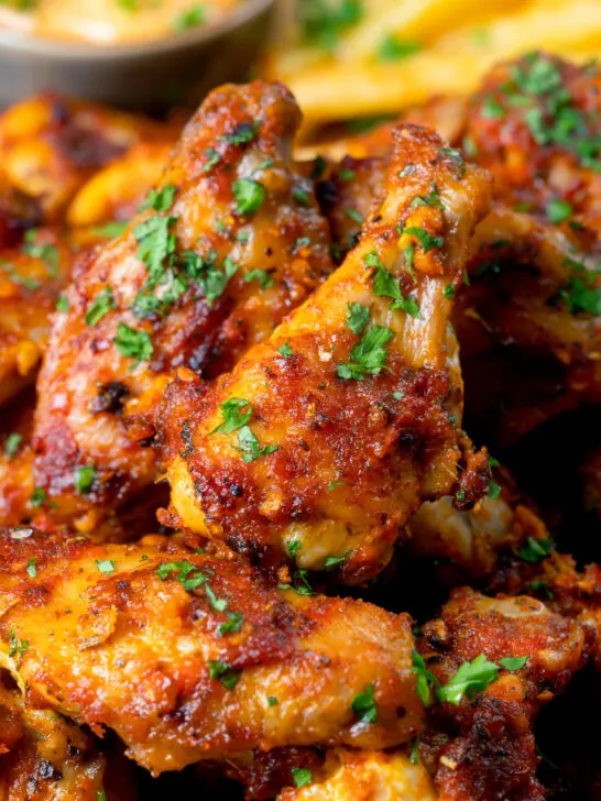 Close-up peri peri chicken wings with fries and spicy mayonnaise.
