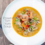Overhead creamy Thai prawn tom yum soup featuring a title overlay.