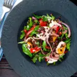 Overhead puy lentil salad with roasted peppers, goat's cheese and rocket featuring a title overlay.