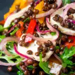 Close-up French lentil salad with roasted peppers, goat's cheese and rocket featuring a title overlay.