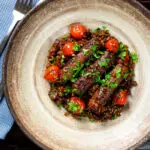 Overhead beef sausage and lentil casserole with cherry tomatoes.