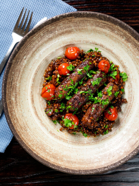 Overhead beef sausage and lentil stew with cherry tomatoes.