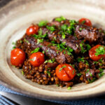 Beef sausage and lentil casserole with cherry tomatoes.
