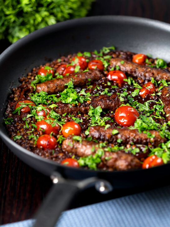 Sausage and lentil stew with cherry tomatoes in the cooking pan.