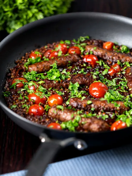 Sausage and lentil stew with cherry tomatoes in the cooking pan.