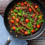 Overhead sausage and lentil casserole with cherry tomatoes in the cooking pan.