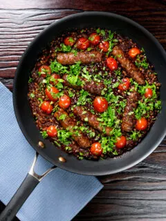 Overhead sausage and lentil casserole with cherry tomatoes in the cooking pan.