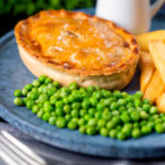 Beef and Stilton pie with chips, garden peas and gravy featuring a title overlay.