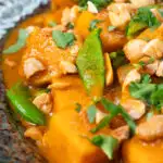 Close-up vegan satay sweet potato curry with a coconut milk sauce featuring a title overlay.