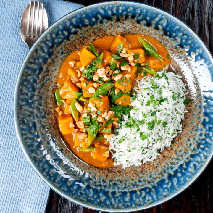 Vegan satay sweet potato curry with chopped peanuts and white rice.