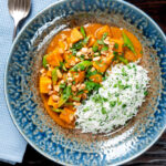 Overhead vegan satay sweet potato curry with a coconut milk sauce featuring a title overlay.