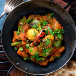 Overhead vegan vegetable bhuna Indian curry served a naan bread.