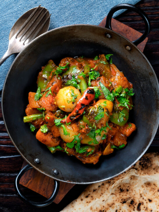 Overhead vegan vegetable bhuna Indian curry served a naan bread.