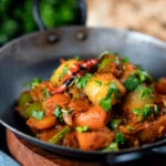 Vegan vegetable bhuna Indian curry served a naan bread.