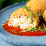 Air fryer arancini with an easy tomato sauce cut open to show filling.