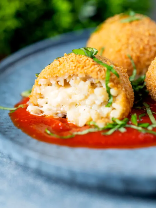 Air fryer arancini with an easy tomato sauce cut open to show filling.