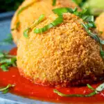 Close-up air fryer cooked arancini with an easy tomato sauce and fresh basil featuring a title overlay.