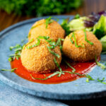 Air fryer cooked mozzarella stuffed arancini rice balls with tomato sauce.