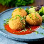 Air fryer cooked mozzarella stuffed arancini rice balls with tomato sauce.