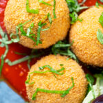 Overhead close-up air fryer cooked arancini with an easy tomato sauce.