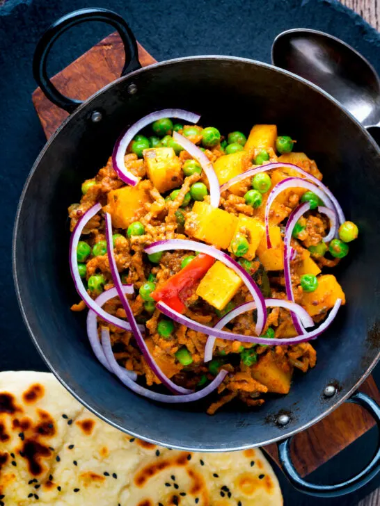Overhead aloo keema or Indian minced beef, pea and potato curry with red onion.