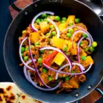 Overhead aloo keema or Indian minced beef, pea and potato curry with red onion featuring a title overlay.