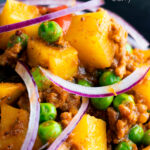 Close-up aloo keema or Indian minced beef, pea and potato curry with red onion featuring a title overlay.