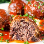 Close-up cut-open pork and black pudding meatball with tomato sauce.