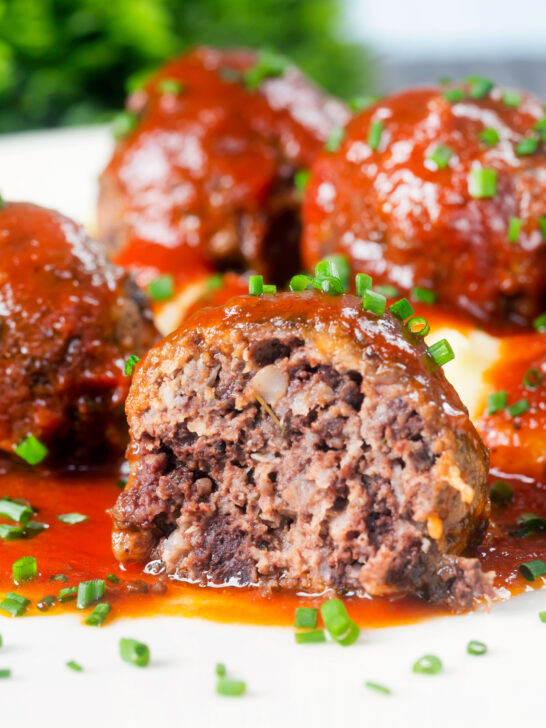 Close-up cut-open pork and black pudding meatball with tomato sauce.