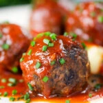 Close-up pork and black pudding meatballs with tomato sauce.
