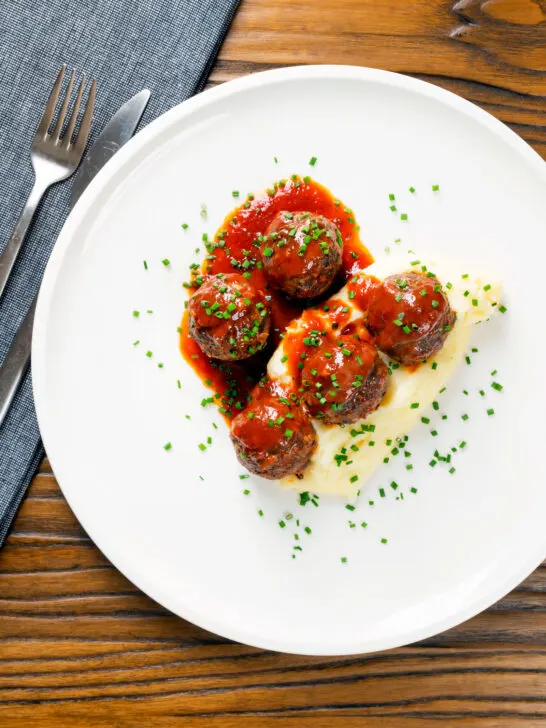 Overhead minced pork and black pudding meatballs with tomato sauce and mashed potato.