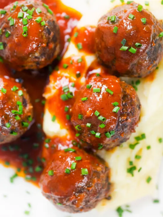 Close-up overhead Minced pork and black pudding meatballs with tomato sauce and snipped chives.
