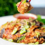 UK Chinese takeaway style chicken egg foo yung omelette being eaten with chopsticks.