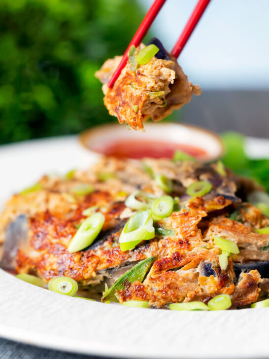 UK Chinese takeaway style chicken egg foo yung omelette being eaten with chopsticks.