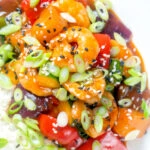 Close-up overhead sweet and sour prawns stir-fry served with rice and spring onions.