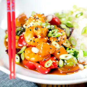 Chinese takeaway style sweet and sour prawns with plain rice and spring onions.